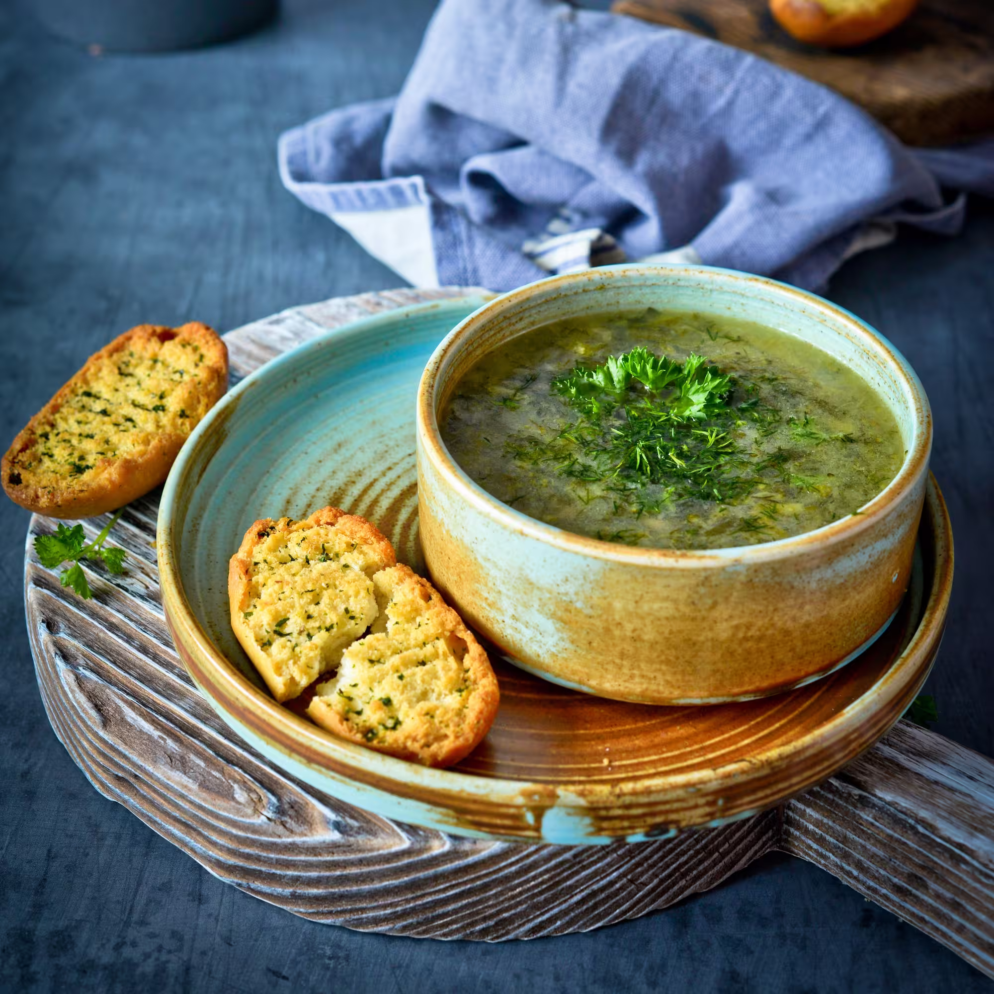 Bowl of green chili, placed on a plate with a side of bread